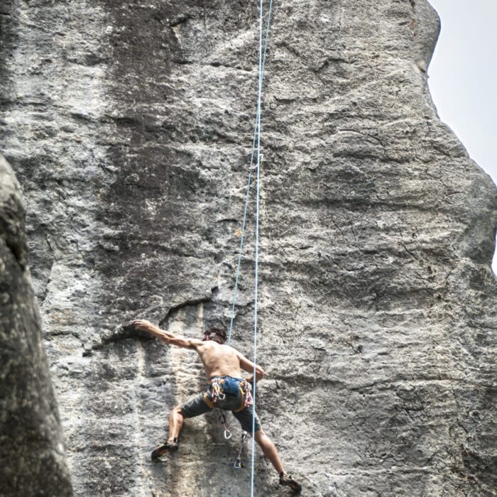 A breathtaking shot of a young male climbing on the high rock in  Champfromier, France